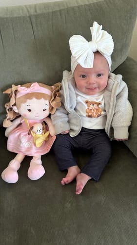 Customer's Personalized Milly Girl doll in a pink dress, sitting next to a baby on a green couch.