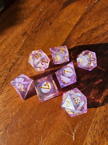 Customer's beautiful Daydream Liquid Core Dice Set in light purple with gold numbers, scattered on a wooden table.