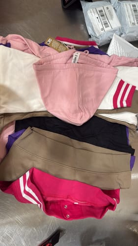 Customer's pile of newly received college hoodies in various bright colors.