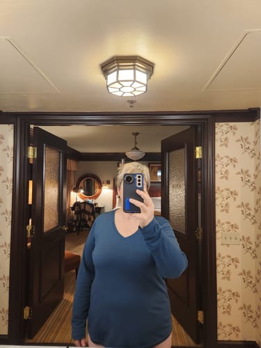 Reviewer taking a mirror selfie wearing the dark blue Millie Long Sleeve top, showing its relaxed fit.