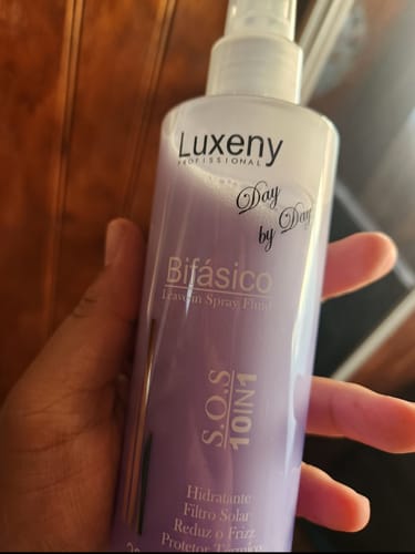 Cliente sostiene el Spray Bifásico 10 en 1, mostrando de cerca el envase morado.