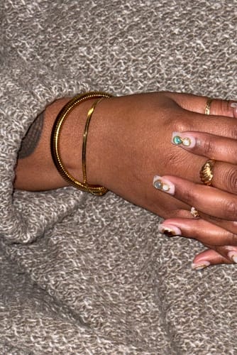 Customer wearing the gold Ibiza Chunky Bangle stacked with another bracelet on their wrist.