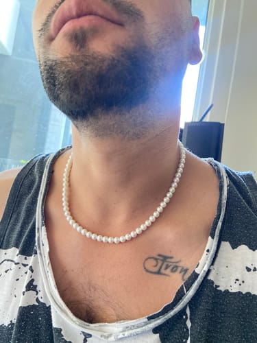 Primer plano de un cliente que lleva puesta la Cadena River Pearls en el cuello.
