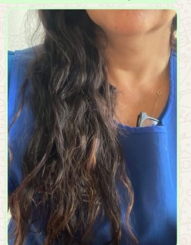 Clienta muestra su cabello largo y ondulado después de usar el Protector Térmico Antifrizz.