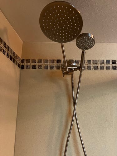 Customer's installed 1-Spray Dual Shower Head Set in a tiled shower, with the rain head angled to the left of the handheld unit.