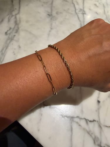 Reviewer wearing the gold Rope Bracelet on their wrist, layered with a paperclip chain bracelet.
