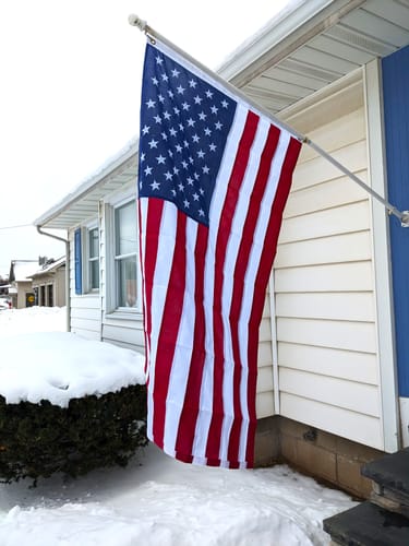 Reviewer's Ultra Heavy Duty American Flag mounted to their house on a snowy day.
