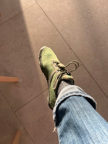 Customer's view of their foot in a green Free I - Barefoot Shoe with cuffed jeans, seen from above.