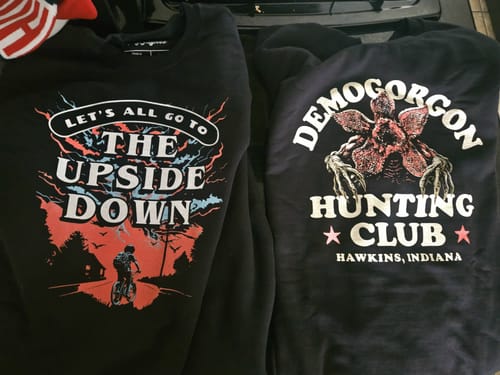 Customer's black Demogorgon Hunting Club Sweatshirt shown alongside another black Stranger Things themed sweatshirt.
