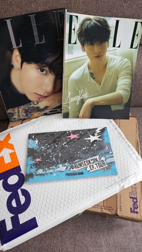 Customer's photo showing two different covers of the BTS JUNG KOOK ELLE magazine laid on top of their delivery package.