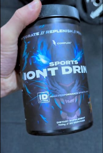 Reviewer holding a black tub of Complex Sports Iont Drink with a prominent blue tiger graphic.