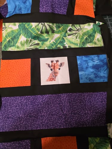 Reviewer's in-progress quilt showing the Baby Safari Animals Giraffe fabric panel sewn with colorful patterned fabric.