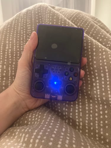 A customer holds the purple RetroGame Pro console in their lap, with the blue power light on.