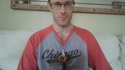 Reviewer sitting on a couch with the Qi Coil™ Mini device resting on their chest.