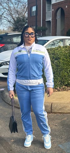 Reviewer standing outdoors wearing the Women's Corsa Track Jacket with the matching track pants as a full suit.