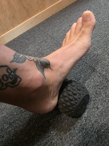 Customer massaging their foot on the textured black Vibit Roll Plus.