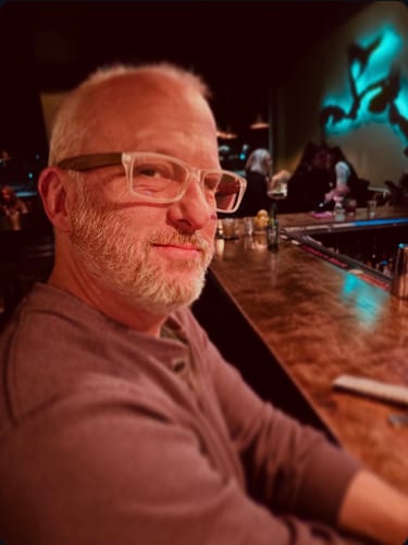 Customer wearing the clear, rectangular Avalon Blue Light Readers in a restaurant.