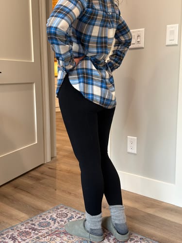 Customer from a back-angle view wearing the form-fitting black Stella Petite leggings with a plaid shirt.