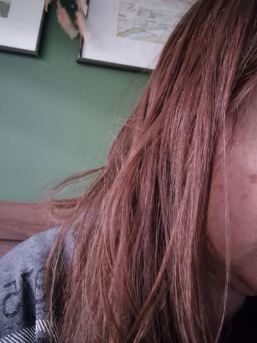 Primer plano del cabello castaño rojizo de una clienta, mostrando su textura tras usar el Spray Bifásico.