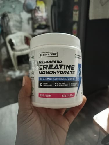 Customer holding a white tub of Wellcore Micronised Creatine Monohydrate, Fruit Fusion flavor.