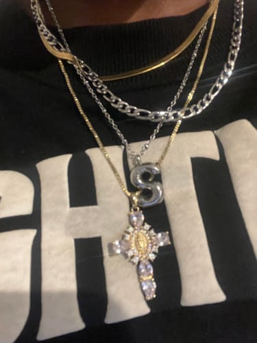 A customer wearing the Valerie Virgin Mary Cross Pendant layered with other gold and silver necklaces.