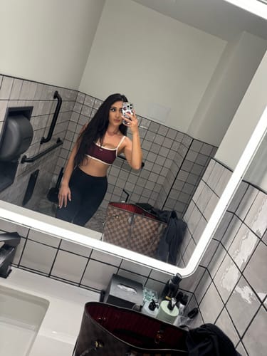Reviewer taking a mirror selfie in a bathroom, wearing the BlackCherry-Cream Micro Bra with black leggings.
