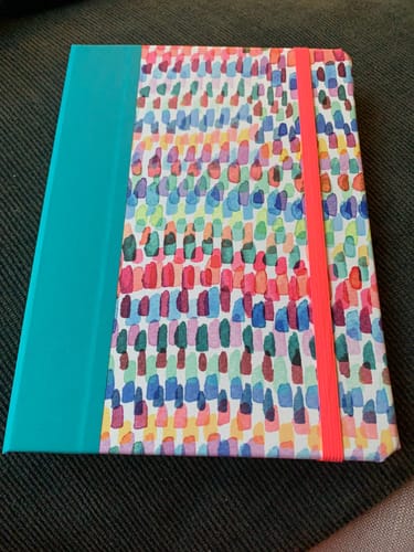 Customer's Custom Book-Style iPad Case with a colorful brushstroke pattern, teal spine, and orange elastic band.