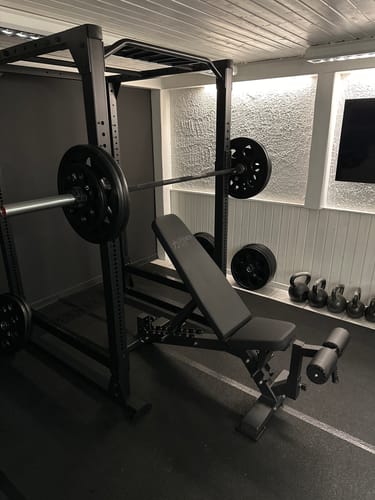 Customer's black Rubber Coated Easy Grip Plates on a barbell inside a home gym power rack.