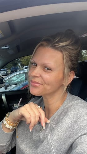 Reviewer wearing the gold Mother of Pearl Teardrop Ring on her index finger while sitting in a car.