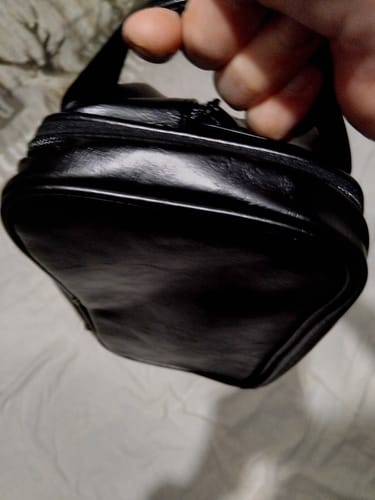 Gros plan de la main d'un client tenant la trousse Max-Barber® noire.