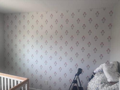 Customer shows a finished accent wall with floral wallpaper, demonstrating the result of using the Application Tool.