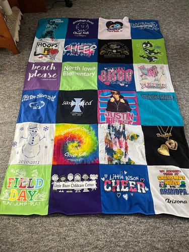 Customer's colorful Premium T Shirt Quilt laid out on a floor, showing a patchwork of various memorable t-shirts.