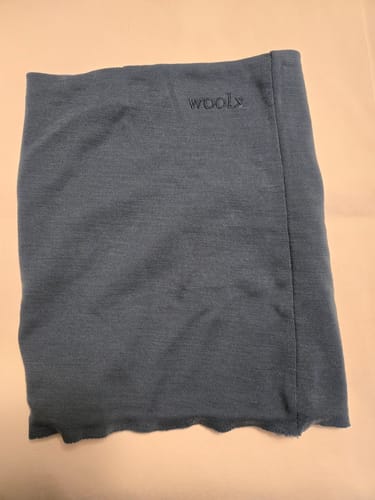 Customer's steel blue Neck Gaiter laid flat, showing the logo and the altered, unhemmed bottom.