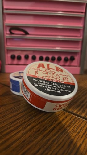 Customer's tin of Sweet Nectar Nicotine Pouches on a wooden surface, with a second tin in the background.