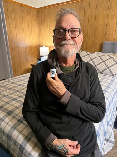 Reviewer holding a bottle of Meraki Blu USP Grade Methylene Blue while seated on a bed.