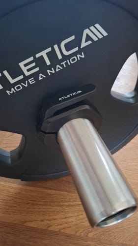 Kundenfoto zeigt einen schwarzen Slim Hantelverschluss, der eine Gewichtsscheibe auf einer Hantelstange sicher fixiert.