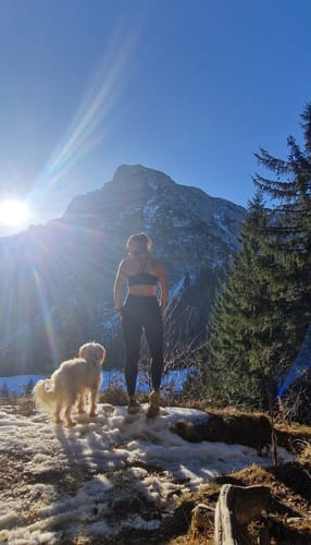 Eine Kundin trägt die Antelao Leggings bei einer sonnigen Wanderung in den verschneiten Bergen.