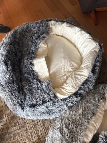 Reviewer's empty Pet Cave Dog Bed, showing the fluffy charcoal exterior and light interior.