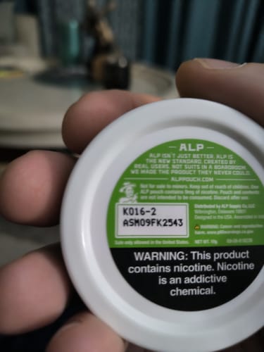 Customer's close-up of the warning label and manufacturing details on the bottom of the Spearmint Nicotine Pouches can.