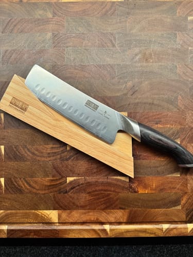 Customer's Japanese Nakiri Knife and its wooden sheath resting on a dark cutting board.