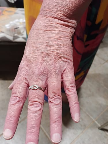 Customer's hand wearing the delicate silver-colored Love Knot Ring on their finger.