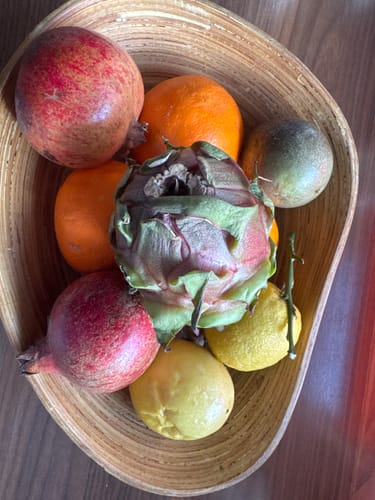 Ein Kunde zeigt die frischen Orangen aus der Bio Orangen-Mixbox in einer Holzschale mit weiterem Obst.