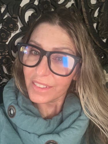 A reviewer wearing the black, square-framed ALDEN BLUE LIGHT READERS.