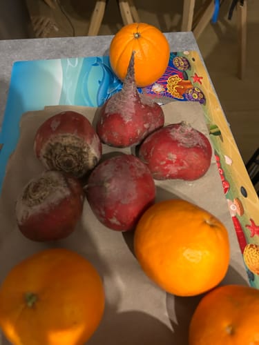 Ein Kunde zeigt mehrere frische Tonda di Chioggia Beten, die auf einem Tisch liegen.