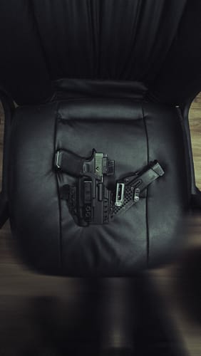 Customer's black APX holster holding a handgun and magazine, displayed on a black leather chair.