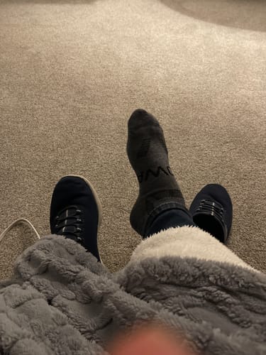 Customer relaxing with their feet up, wearing one dark grey Men's Alpaca Sock.