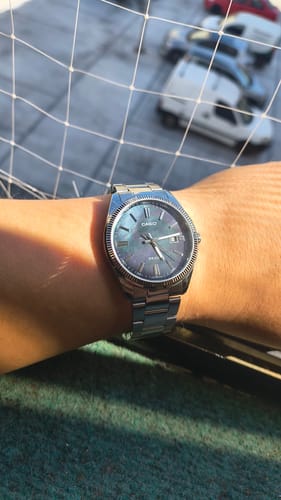 Cliente con el reloj Casio análogo en la muñeca, mostrando la esfera tornasol y la correa de acero.