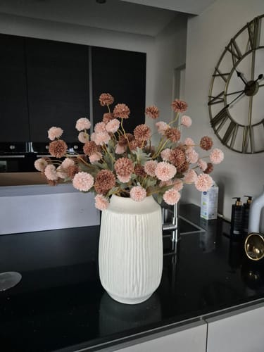 Klant toont een volle bos Zijden Kiku Bloemen in een witte vaas op een aanrecht.
