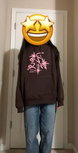 Reviewer shows the fit of the brown TXT x ISTKUNST Hoodie paired with blue jeans.