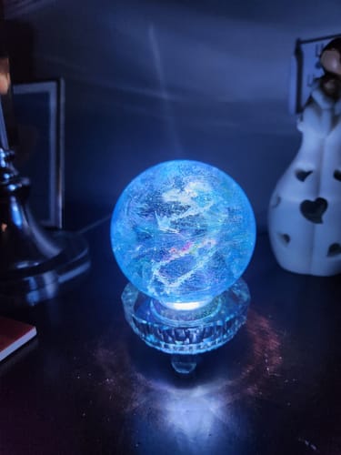 Reviewer's glowing blue Dichroic Explosion Orb on a lighted base, showing visible swirls.